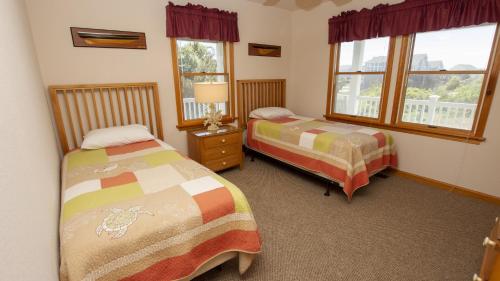 a bedroom with two beds and two windows at Oceanside, 7 BRs, ELEVATOR, Private Pool, Hot Tub, OH3, Aurora in Corolla