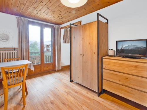 - un salon avec une télévision, une table et un meuble de télévision dans l'établissement Studio cosy avec balcon et piscine à Serre Chevalier, à 300m des pistes - FR-1-762-11, à Saint-Chaffrey