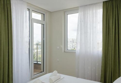 1 dormitorio con 2 ventanas y 1 cama con toallas en Brand New Modern 1BD Flat In Chayka with Parking, en Varna