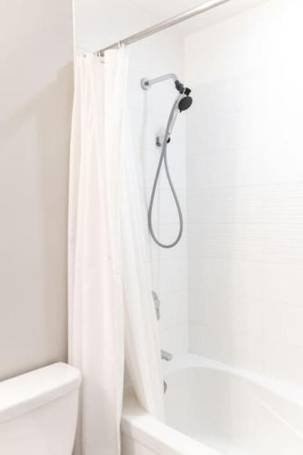 a white bathroom with a shower curtain and a toilet at City Serenity 1 Bedroom with Balcony in Toronto