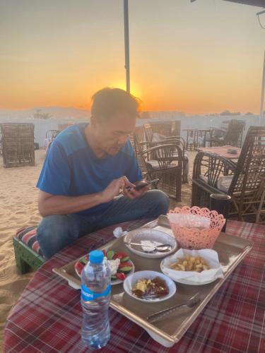 mężczyzna siedzący przy stole z tacą z jedzeniem w obiekcie Nuba Heart w mieście Aswan