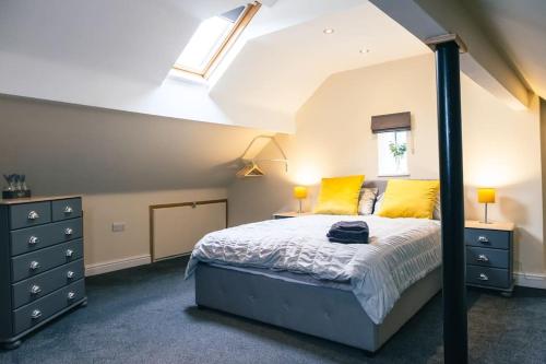a bedroom with a bed with yellow pillows and a window at 4 bedroom - Sleep 9 home in Cheadle Staffordshire - Alton towers Dimmingsdale Peak District Trentham Gardens Water World in Cheadle