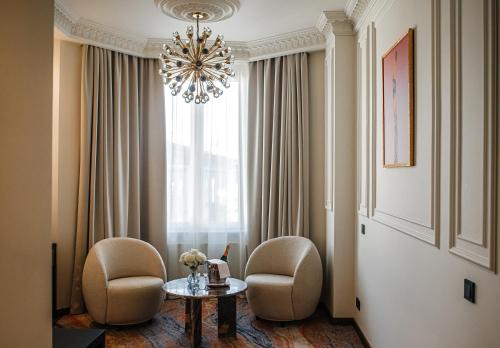 a room with two chairs and a table and a chandelier at Nadiya Palace in Ivano-Frankivsʼk
