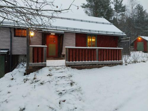 una casa con una puerta roja en la nieve en Vargheden Bed & Breakfast, en Malung