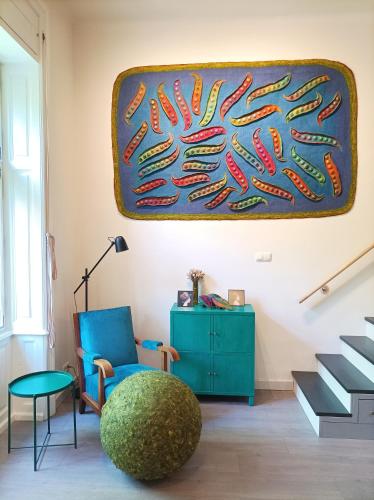 a living room with a blue chair and a painting on the wall at Art & Craft Apartment in Kecskemét