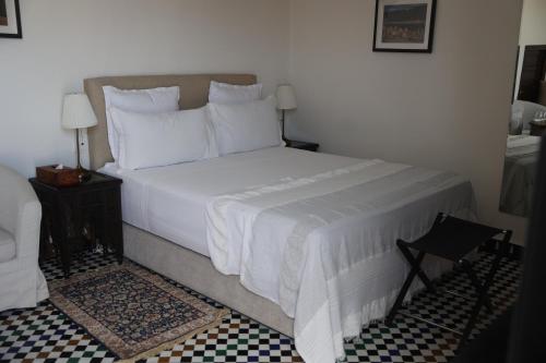 a bedroom with a large bed with white sheets and pillows at Riad Batchisarai in Fès