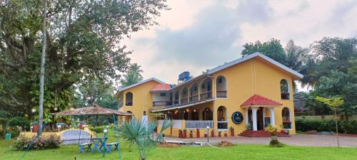 una casa amarilla con un patio con mesas y sillas en Carina Beach Resort - 10mins walk to Benaulim Beach, en Benaulim