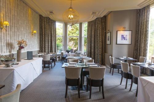 a dining room with tables and chairs and windows at Rosslea Hall Hotel in Rhu
