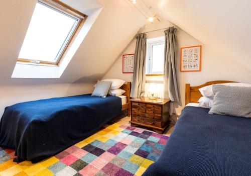 a attic bedroom with two beds and a rug at Bwthyn Capten - a charming cottage for up to 6 in Newport Pembrokeshire