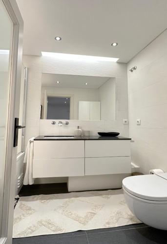 a white bathroom with a sink and a toilet at Groovy Caparica Gem with Large Sunny Terrace in Costa da Caparica