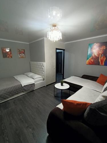 um quarto com 2 camas, um sofá e um lustre em Квартира в центре с гостиничным сервисом. em Petropavl