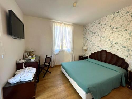 a bedroom with a bed and a desk and a television at Hotel Clelia in Deiva Marina