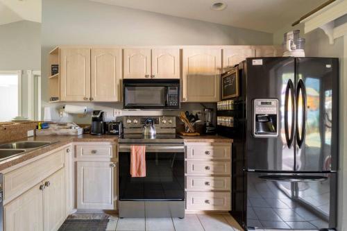 a kitchen with white cabinets and a black refrigerator at Tropical Island Escape Near Disney, Beach, Cruise in Merritt Island