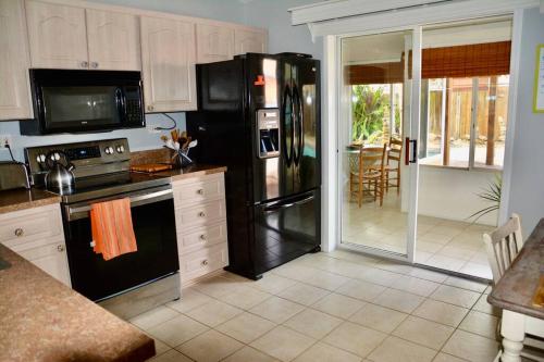 a kitchen with a black refrigerator and a stove at Tropical Island Escape Near Disney, Beach, Cruise in Merritt Island