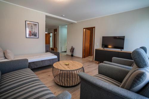 a living room with a couch and a bed and a tv at Hotel CityHome am Kurpark in Bad Salzuflen