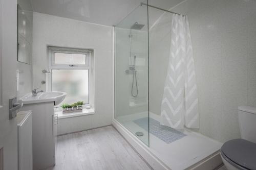 a white bathroom with a shower and a sink at Lovely Home in Blackpool For You in Blackpool