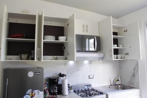 a kitchen with white cabinets and a sink and a refrigerator at Casa flores Residencial Privada Nueva San miguel in San Miguel