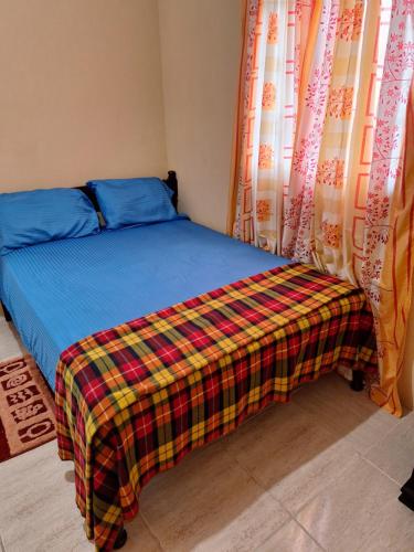 een bed met een deken erop in een kamer bij psalms in Cunupia Village