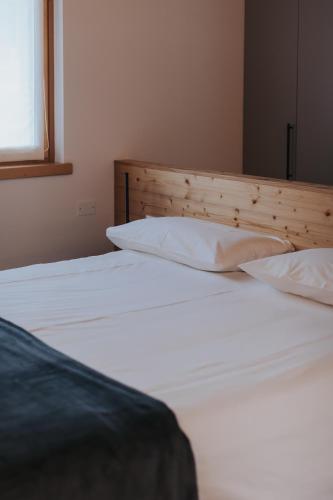 a bedroom with two beds with white sheets and a window at Falcade Lodge in Falcade