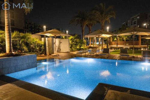 duży basen w nocy z parasolami w obiekcie Cairo Festival City Premium Serviced Residences w Kairze