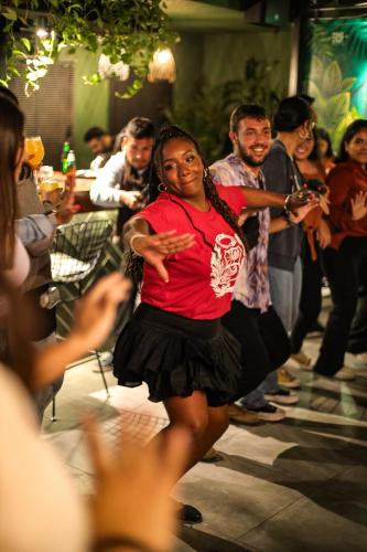 a woman dancing in front of a crowd of people at Black Llama Hostel Miraflores in Lima