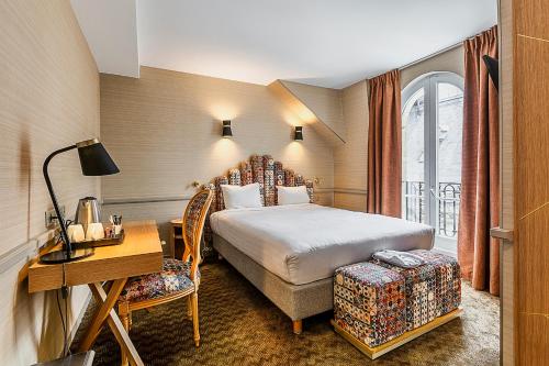 Una habitación de hotel con una cama, un escritorio y una ventana. en Hotel La Manufacture, en París
