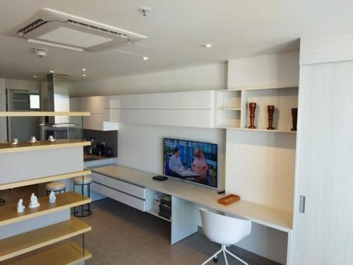 a kitchen with white cabinets and a desk with a tv at Distrito 90 in Barranquilla