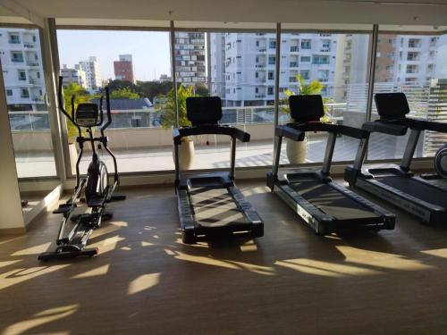 un gimnasio con cintas de correr en un edificio con una gran ventana en Distrito 90 en Barranquilla