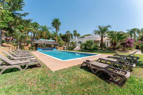 a swimming pool with lounge chairs and a house at Villa Natura by Algarve Holidays in Vilamoura