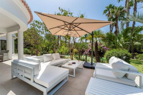 a patio with white furniture and an umbrella at Villa Natura by Algarve Holidays in Vilamoura