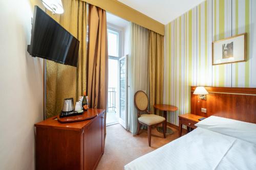 a hotel room with a bed and a desk and a chair at Hotel Raffaello Prague in Prague
