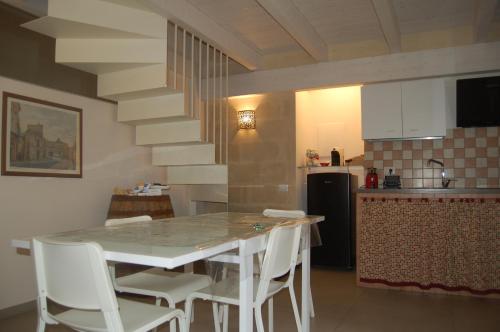 a kitchen with a table and white chairs in a room at Le 2 Gravine nei Sassi in Matera