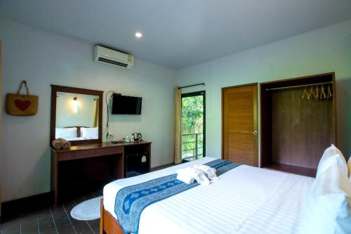 1 dormitorio con cama, escritorio y espejo en Plawan lipe Bungalows en Ko Lipe