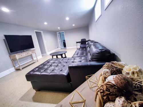 a living room with a black leather couch and a flat screen tv at Aurora House in Aurora