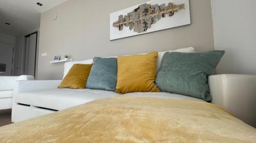 a white couch with yellow and blue pillows on it at HOUSE TERRAZA PREMiUM 6PAX WIFI in Sierra Nevada
