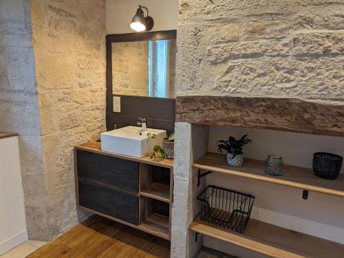 une salle de bain avec un lavabo et un mur en pierre dans l'établissement Maison de Bourg Cressensac, à Cressensac