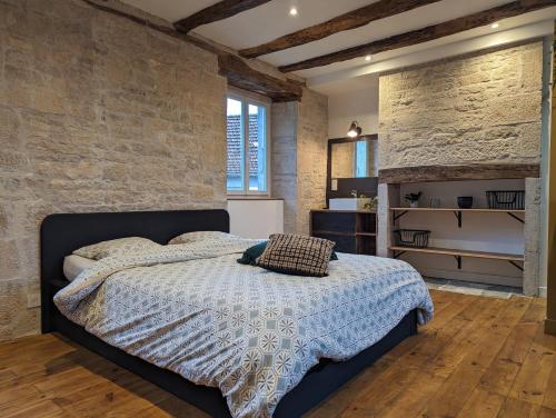 une chambre avec un lit et un mur de briques dans l'établissement Maison de Bourg Cressensac, à Cressensac