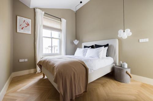 sypialnia z dużym białym łóżkiem i oknem w obiekcie The Notting Hill Apartments By Hok Living - Nh4 w Londynie