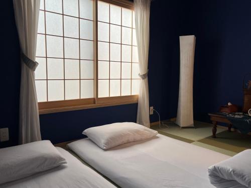 a blue room with two beds and a window at Inari-Home in Kyoto