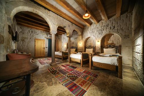 a bedroom with two beds and a stone wall at Caverna Hotel Premium Caves in Göreme
