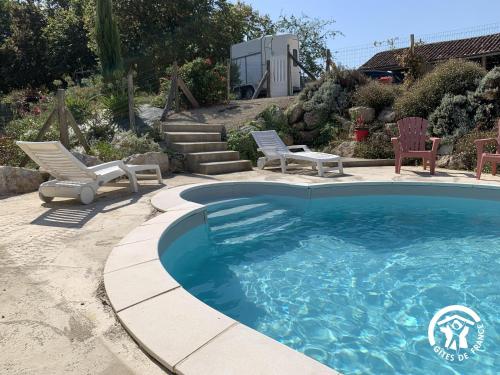 a swimming pool with two lawn chairs and two chairs at Le Pigeonnier de Bouheben in Verlus