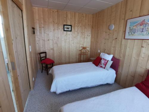 - une chambre avec deux lits et une chaise rouge dans l'établissement Le Pigeonnier de Bouheben, à Verlus