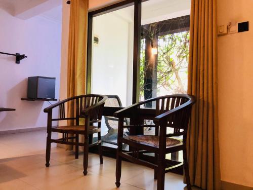 dwa krzesła i stół w pokoju z oknem w obiekcie Dambulla Rock Arch w mieście Dambulla