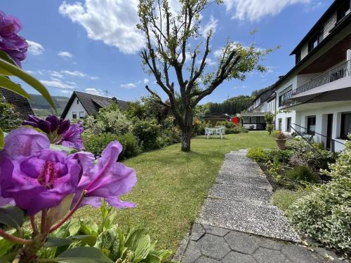 un jardin avec des fleurs violettes et un arbre dans l'établissement Riedel Fronz, à Lennestadt