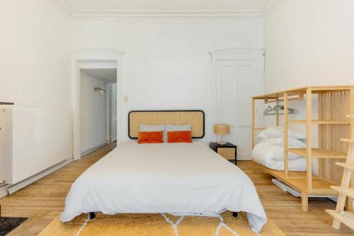 a bedroom with a large white bed with orange pillows at Le Studio en Feronstrée in Liège