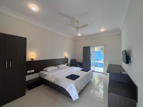 a white bedroom with a bed and a window at Morjim Sunset Guesthouse- Apartments with Kitchen & AC Rooms in Morjim