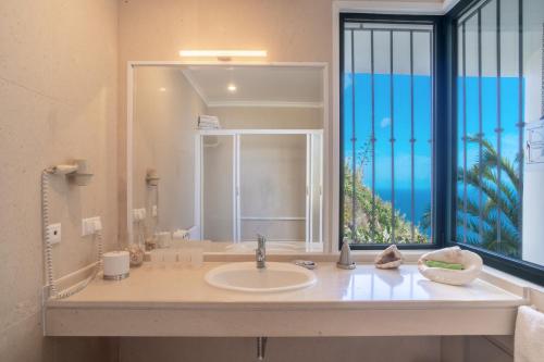 een badkamer met een wastafel en een groot raam bij Villa Amelia in Falésia by the Sea in Caniço