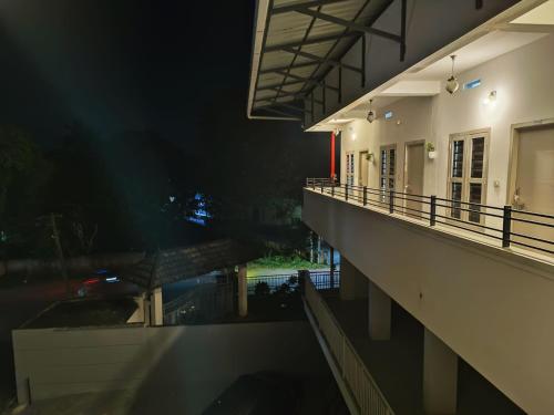 a balcony of a building at night with a reflection in the water at SN Residency in Kalpetta