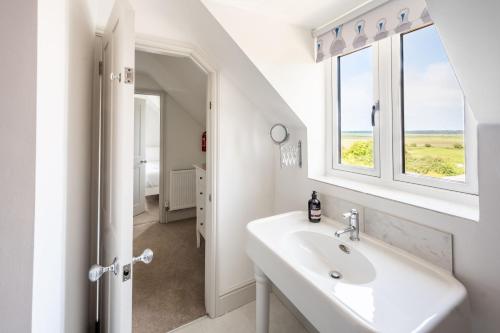 a white bathroom with a sink and a window at Neptune House in Wells next the Sea