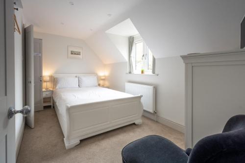 a white bedroom with a white bed and a window at Neptune House in Wells next the Sea